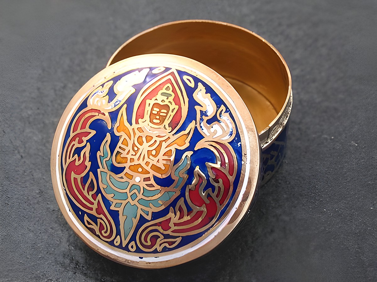 Multifunktionale Dose rund mit einer blauen und roten Figur auf dem Deckel, hergestellt von Juwelier Harnisch, ohne Stein, geöffnet und auf schwarzem Untergrund platziert.