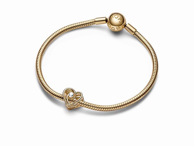 Ein feines Armband aus 585 Gelbgold mit einem offenen, gewundenen Herz Charm und einer behandelten Süßwasserzuchtperle, gefertigt von Pandora, Modell SHINE.
