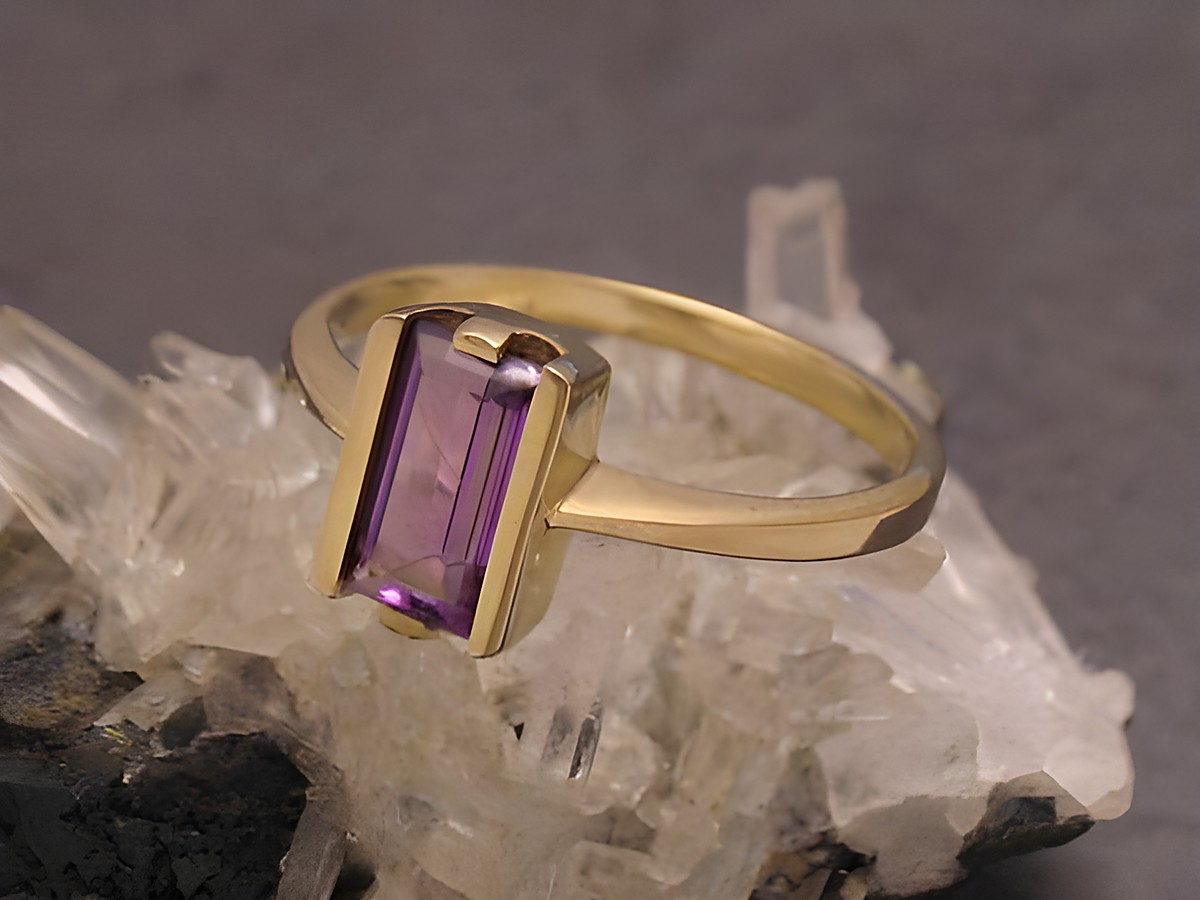 Goldring puristisch aus Gold 333 mit Amethyst in Größe 56, Hersteller Juwelier Harnisch, bis Größe 56/18, elegant und zeitlos, auf einem mineralischen Untergrund präsentiert.