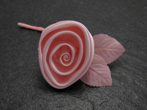 Zarter Haarschmuck in Form einer pastellrosa Satinrose mit Blatt, hergestellt von Juwelier Harnisch, ideal für eine elegante Frisur oder als Brosche.