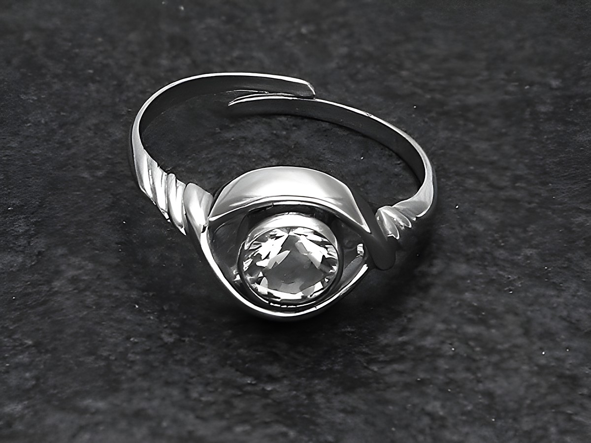 Silberring rho ELEGANT in verstellbarer Größe mit einem großen Bergkristall, rhodiniert, hergestellt von Juwelier Harnisch, auf dunklem Hintergrund abgebildet.