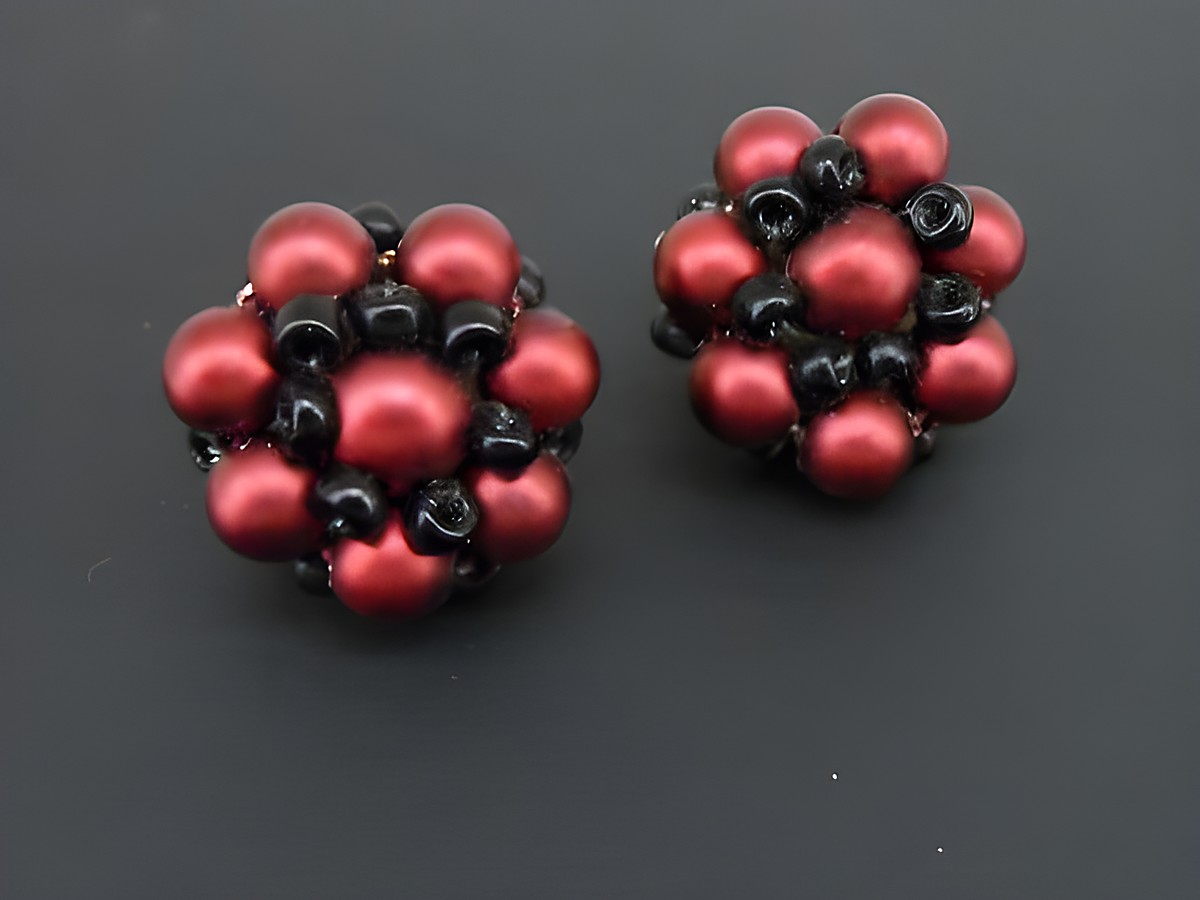 Dunkelrot-schwarze blumige Ohrclips mit goldfarbenen Details und seidenmatten synthetischen Zuchtperlen, hergestellt von Juwelier Harnisch.