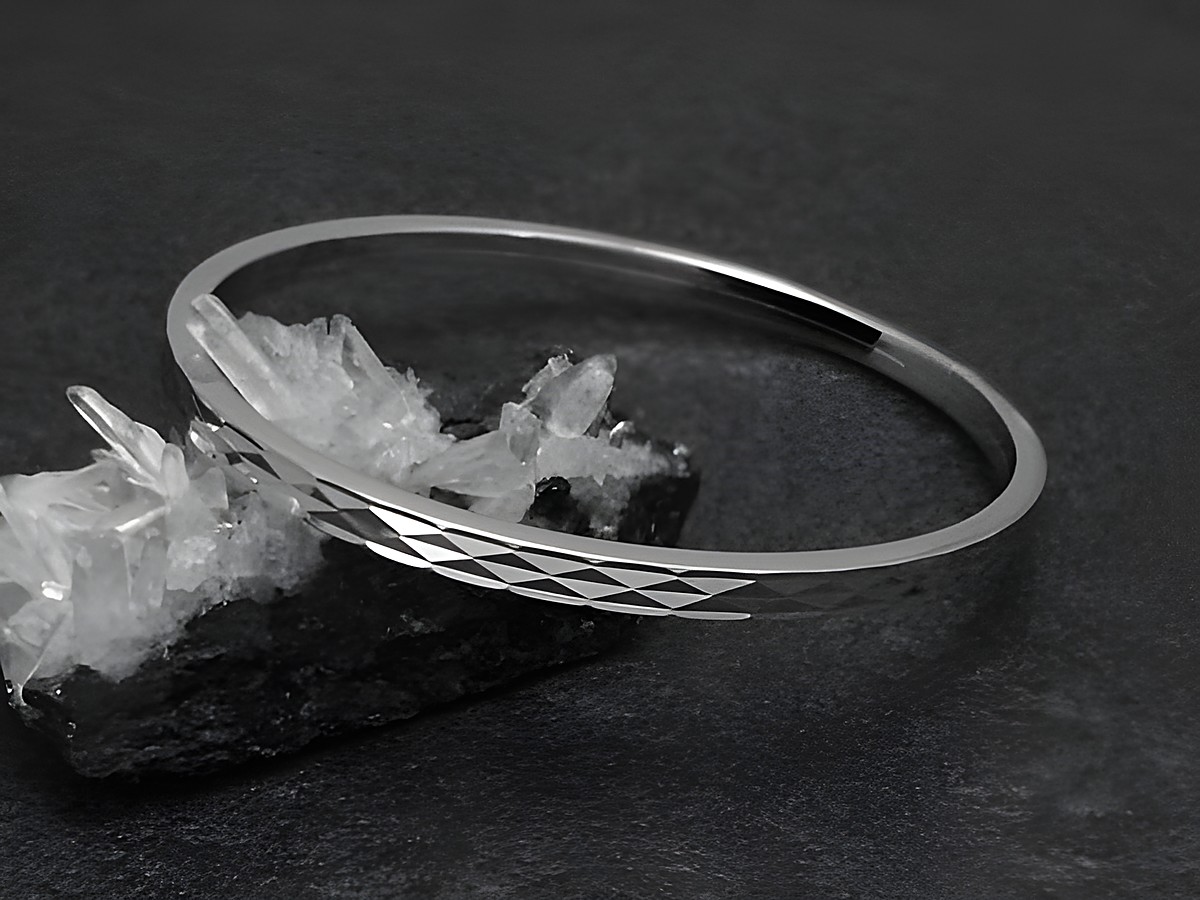 Silber Armreifen funkeln in rhodiniertem Finish, 4 mm breit, 18 cm lang, elegant auf einem schwarzen Untergrund mit Kristallen drapiert. Hersteller Juwelier Harnisch.