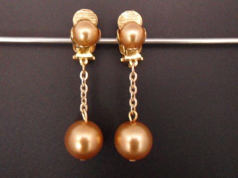 Glänzende goldfarbene Ohrclips mit einem zeitlosen Design aus Kunstharz, verbunden durch eine feine Kette, die edel und elegant wirkt, Hersteller Juwelier Harnisch.