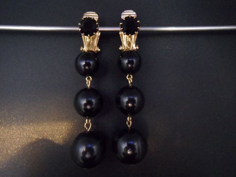 Ohrclip in schwarz zeitlos mit goldfarbenen Elementen und Kunstharz. Hersteller Juwelier Harnisch. Elegantes Design mit hängenden, runden Details. Ideal für besondere Anlässe.
