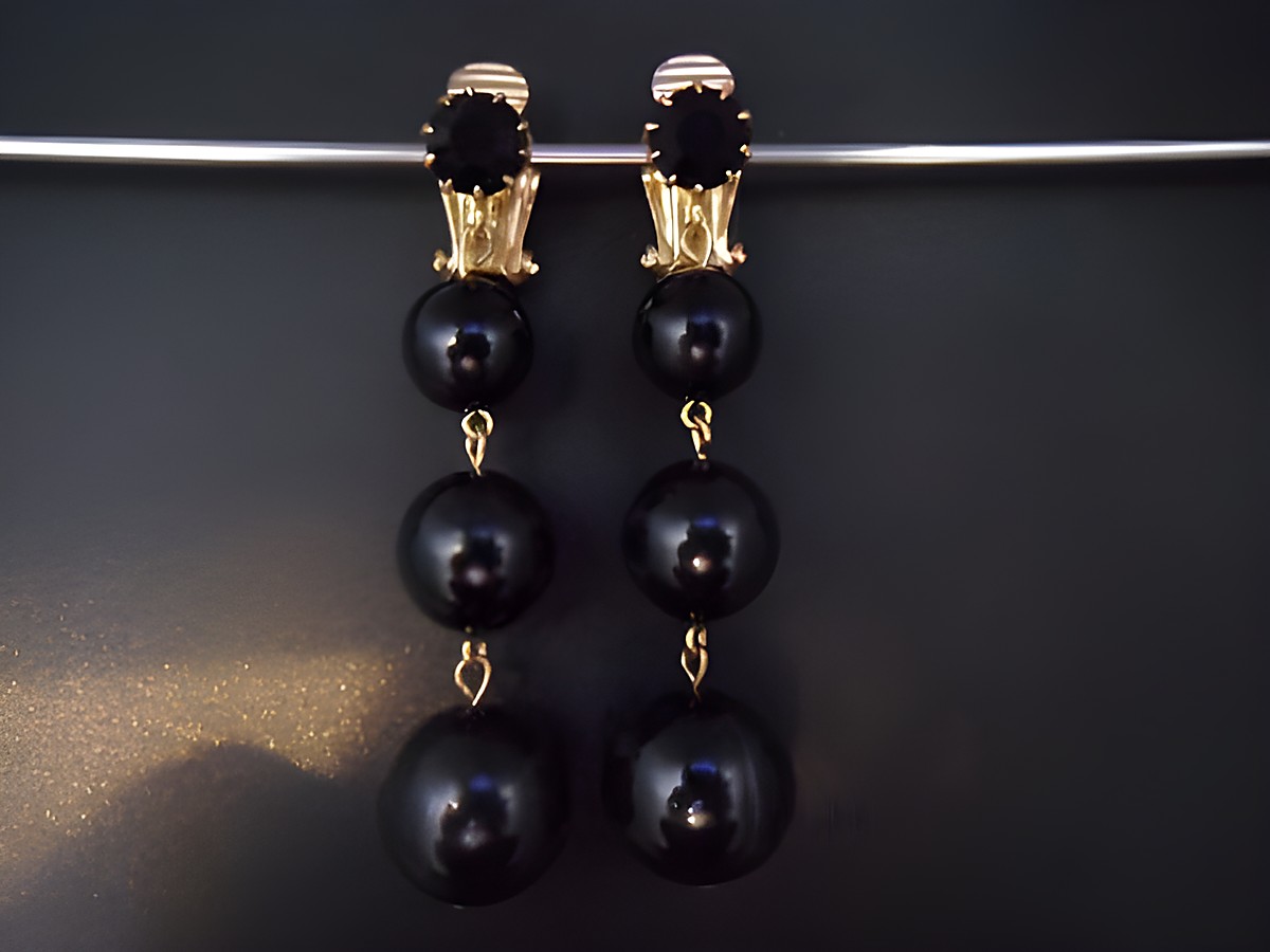 Ohrclip in schwarz zeitlos mit goldfarbenen Elementen und Kunstharz. Hersteller Juwelier Harnisch. Elegantes Design mit hängenden, runden Details. Ideal für besondere Anlässe.