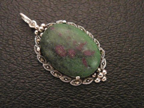Cabochon Rubin in Zoisit Silber Medaillon Anhänger von Juwelier Harnisch mit filigraner Umrandung, der grüne Stein zeigt rötliche Einschüsse und ist glänzend poliert.