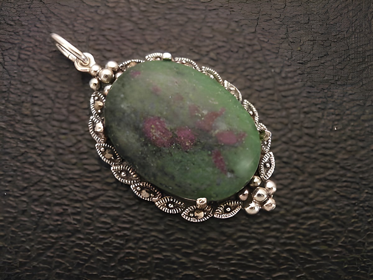 Cabochon Rubin in Zoisit Silber Medaillon Anhänger von Juwelier Harnisch mit filigraner Umrandung, der grüne Stein zeigt rötliche Einschüsse und ist glänzend poliert.