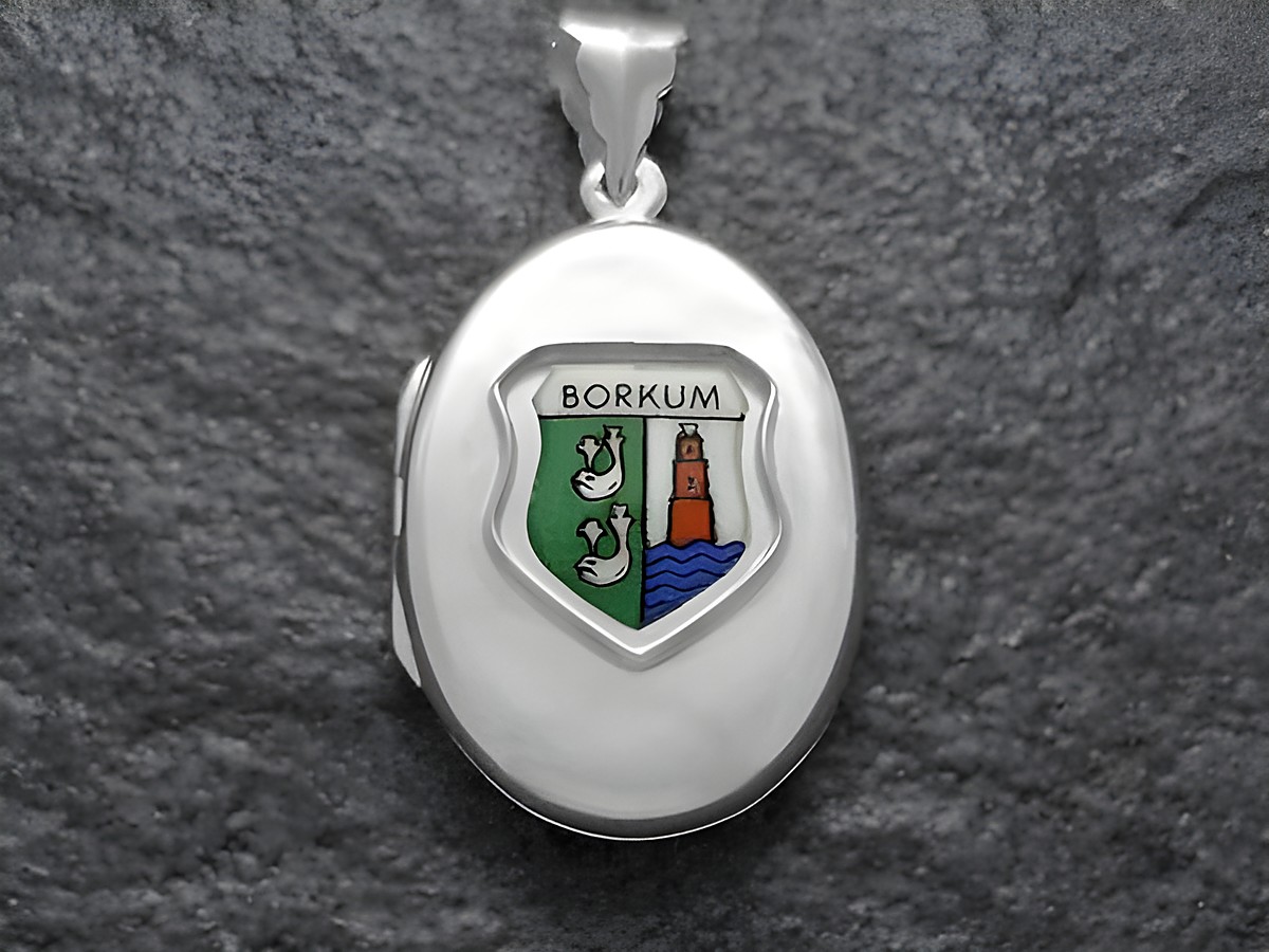 Silbernes Medaillon mit dem Inselwappen von Borkum, das eine grüne und blaue Farbgebung zeigt, mit stilisierten Meerestieren und einem Leuchtturm. Hersteller ist Juwelier Harnisch.
