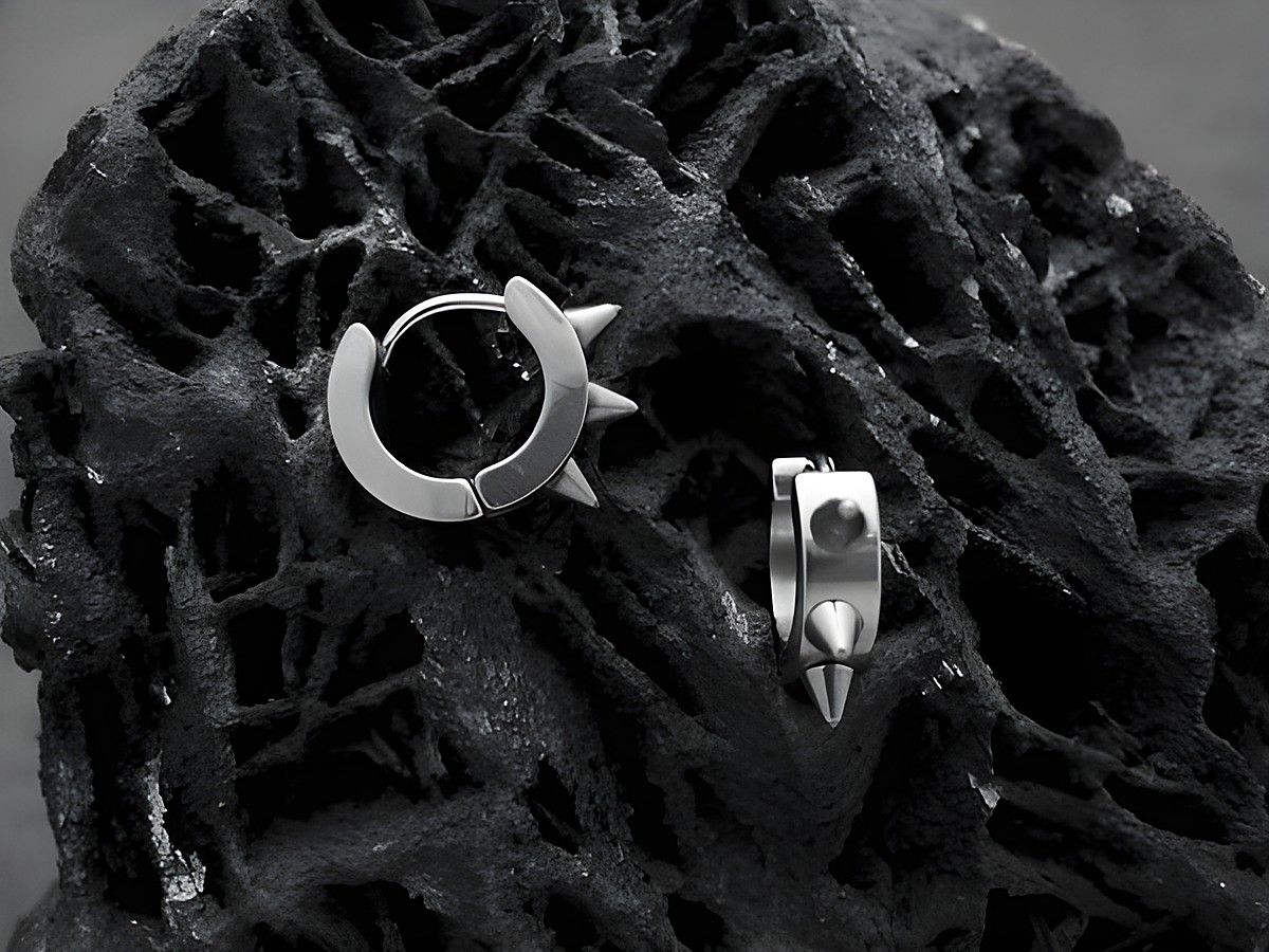 Edelstahl Creolen mit SPIKES von Juwelier Harnisch, modern und trendy, perfekt für einen stylishen Look, auf einem schwarzen, strukturierten Hintergrund.
