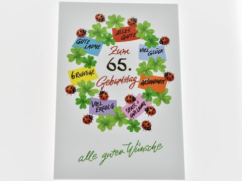 Die Geburtstagskarte zeigt einen bunten Kranz aus Glücksklee und Marienkäfern, umrahmt von verschiedenen Glückswünschen für einen 65. Geburtstag. Hersteller: Juwelier Harnisch.