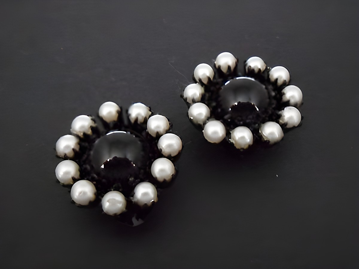 Schwarz-grauer, zeitloser Ohrclip aus Kunstharz mit einer glänzenden, schwarzen Mitte und umlaufenden, silbernen Perlen. Hersteller ist Juwelier Harnisch.