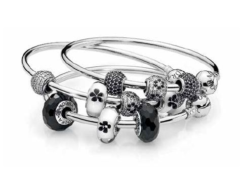 Silber Armreifen von Pandora mit 21 cm Länge, verziert mit verschiedenen Charms, darunter schwarze und silberne Elemente, ideal zum individuellen Gestalten.
