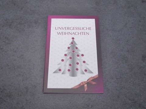 Eine Grußkarte mit dem Titel Unvergessliche Weihnachten, die ein stilisiertes Weihnachtsbaum-Motiv in Grau und pinken Punkten zeigt. Die Karte ist rosa umrandet und hat ein schmales Satinband.