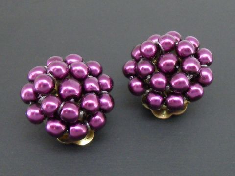 Dunkellila Ohrclips aus synthetischen Zuchtperlen mit goldfarbenen Elementen, Hersteller Juwelier Harnisch, elegant und auffällig.