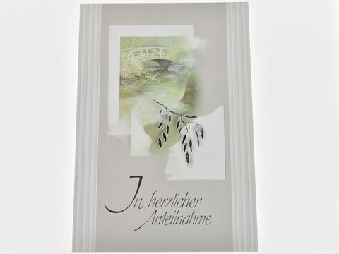 Trauerkarte mit sanftem Motiv einer Brücke und einem fließenden Gewässer, verziert mit einem Blatt. Text in eleganter Schrift: In herzlicher Anteilnahme. Hersteller: Juwelier Harnisch.