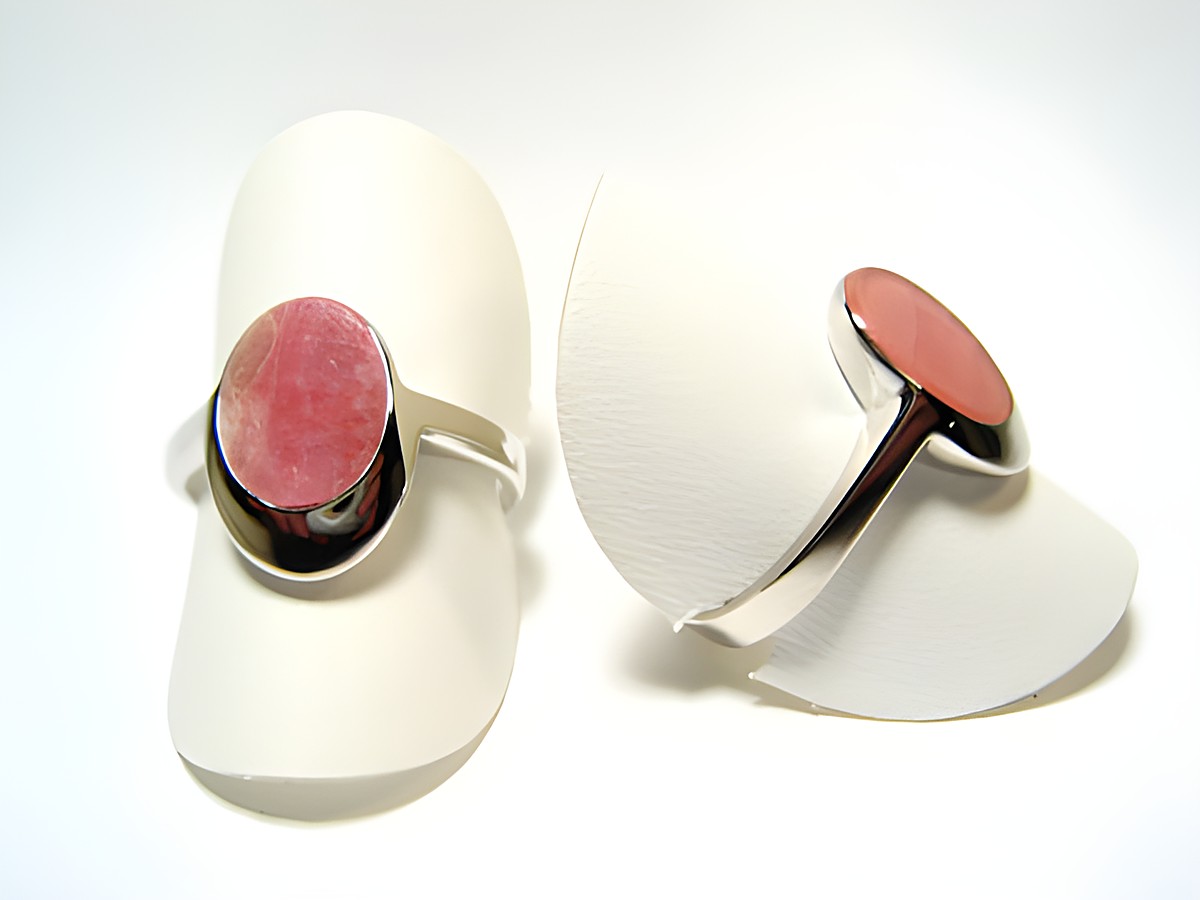 Silber Ring rhodiniert mit Rhodochrosit in rosa, Hersteller Juwelier Harnisch, verstellbare Ringe auf Schmuckständern präsentiert.