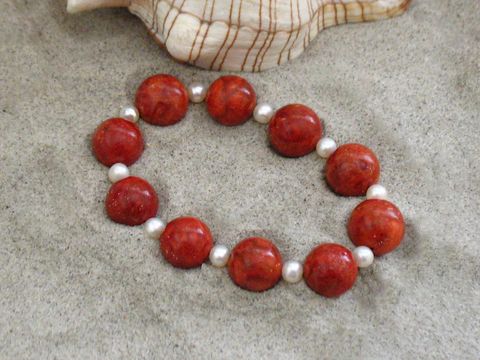 Korallenschmuck Armband 20 cm Gummizug mit Zuchtperlen in rot und weiß, hergestellt von Juwelier Harnisch, schön auf sandigem Hintergrund präsentiert.