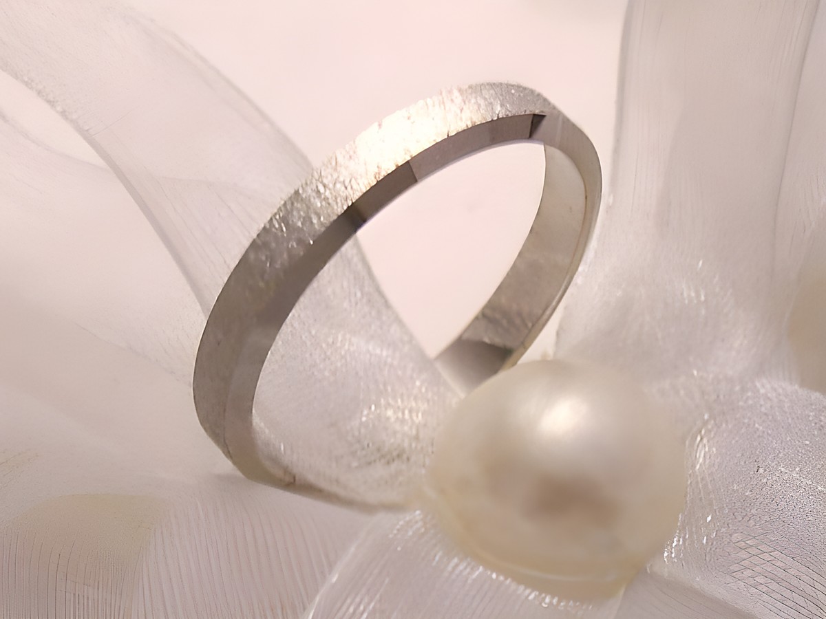 Trauring Ehering WHITE EMOTION aus Weißgold 333, Größe 60/19,1, präsentiert auf einem zarten satinartigen Untergrund mit einer Perle, elegant und schlicht im Design.