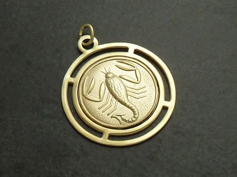 Goldfarbene, runde 3D-Platte mit dem Sternzeichen Skorpion, detaillierte Darstellung des Skorpions im inneren Kreis, elegant gestaltet, Hersteller Juwelier Harnisch.