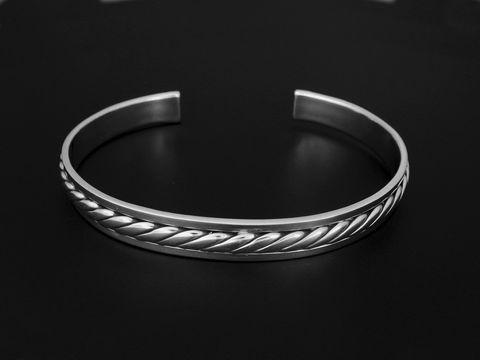 Silber Armreifen - 18 cm - trendig, Hersteller: Juwelier Harnisch, eleganter Armreif mit geflochtenem Design, glänzende Oberfläche auf schwarzem Hintergrund.