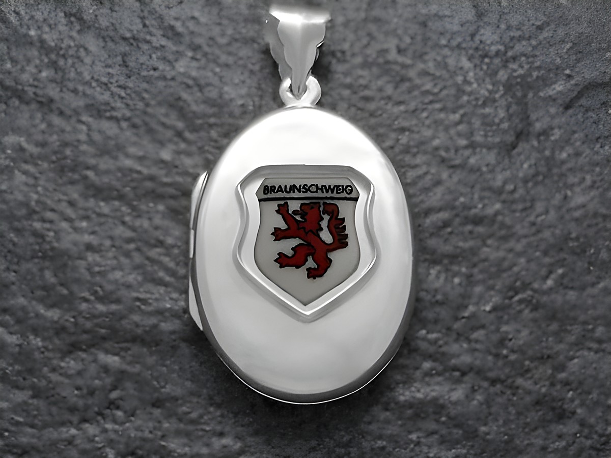 Das Bild zeigt ein silbernes Medaillon mit dem Wappen der Stadt Braunschweig, das einen roten Löwen auf weißem Grund darstellt. Das Medaillon ist vom Juwelier Harnisch in Niedersachsen gefertigt.