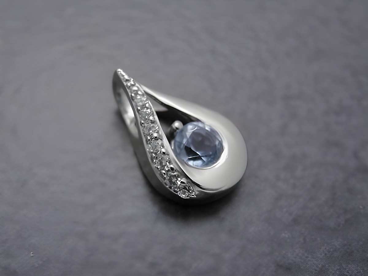 Anhänger in Tropfenform aus rhodiniertem Sterling Silber mit einem blauen Topas und Zirkonia, hergestellt von Juwelier Harnisch, edles Schmuckstück mit zusätzlichen Steinen.