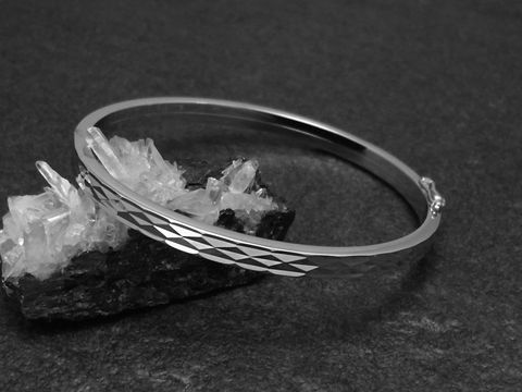 Silber Armreifen im Disco-Look, 4,8 mm rhodiniert, 18 cm, Hersteller Juwelier Harnisch, elegant mit facettierten Oberflächen, auf schwarzem Hintergrund präsentiert, hebt sich stilvoll ab.