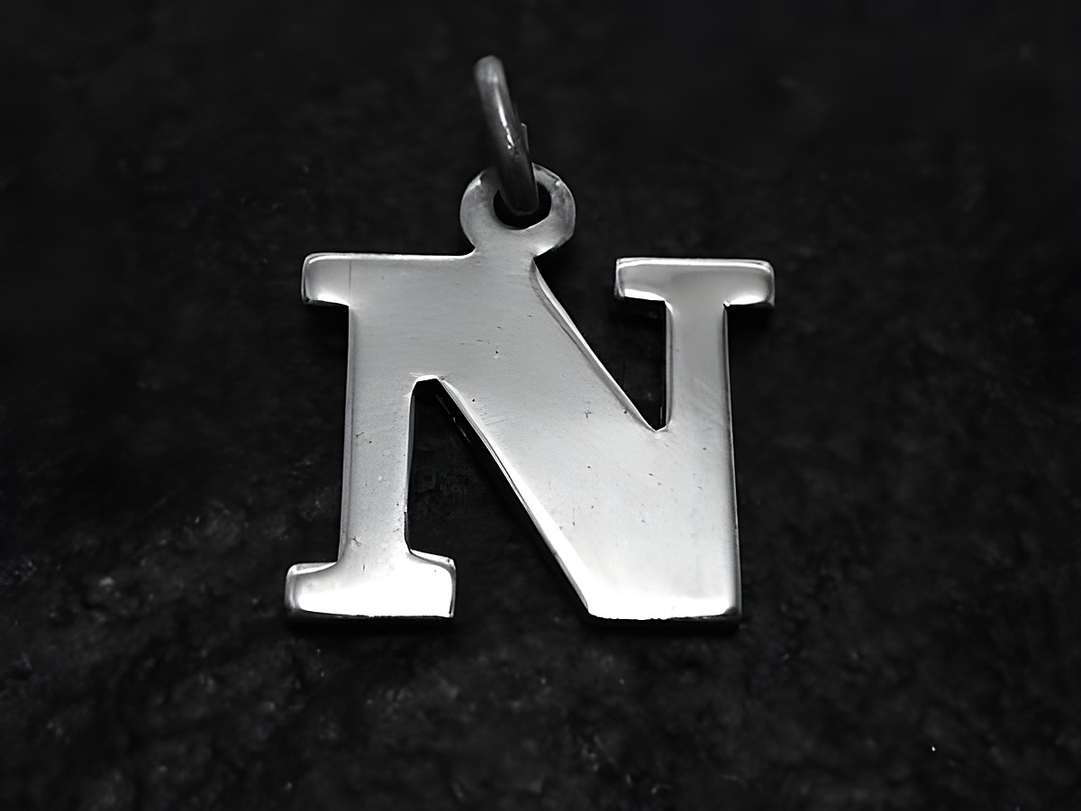 Silberanhänger in Form des Buchstabens N, 15 mm groß, hergestellt von Juwelier Harnisch, auf schwarzem Hintergrund. Ideal zum persönlichen Tragen oder als Geschenk.