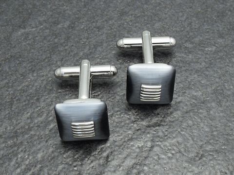 Silberfarbene Manschettenknöpfe mit grau-schwarzen Elementen und dezentem Streifenmuster, Hersteller: Juwelier Harnisch, stilvolle Ergänzung für formelle Outfits.