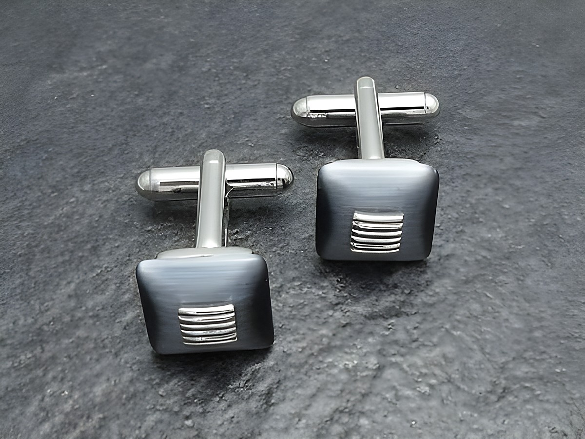 Silberfarbene Manschettenknöpfe mit grau-schwarzen Elementen und dezentem Streifenmuster, Hersteller: Juwelier Harnisch, stilvolle Ergänzung für formelle Outfits.