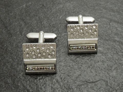 Manschettenknöpfe in silberfarben mit weißen Strass Steinen, Hersteller Juwelier Harnisch, modernes Design mit glänzender Oberfläche und dekorativem Strassband. Ideal für elegante Anlässe.