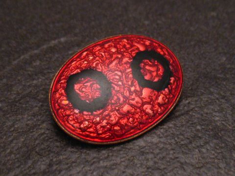 Emaille Brosche in roter und schwarzer Farbgestaltung, oval mit strukturiertem Muster und zwei schwarzen Kreisen, vergoldet, Hersteller Juwelier Harnisch, Vintage-Design.