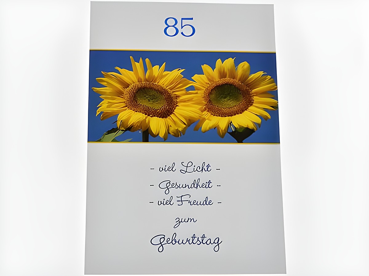 Geburtstagskarte mit zwei Sonnblumen auf blauem Hintergrund, in der oberen Ecke die Zahl 85, darunter der Schriftzug viel Licht, Gesundheit, viel Freude zum Geburtstag. Hersteller Juwelier Harnisch.