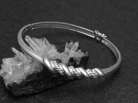 32642-0 Silber Armreifen verdreht 6,9 mm rhodiniert 17 cm, Hersteller Juwelier Harnisch, in stilvoller Anordnung auf schwarzem Untergrund mit kristalliner Struktur im Hintergrund.