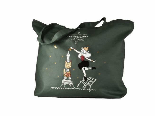 Einkaufsbeutel von Les Georgettes mit einer stilisierten Grafik, die eine Figur zeigt, die den Eiffelturm mit einer Tasse ziert, vor sternenklarem Himmel und Mond, grüne Stoffoberfläche.