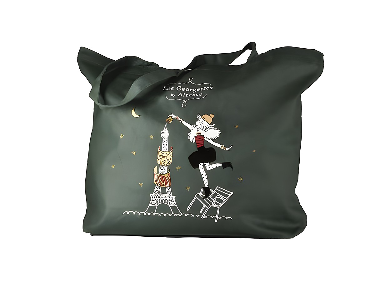 Einkaufsbeutel von Les Georgettes mit einer stilisierten Grafik, die eine Figur zeigt, die den Eiffelturm mit einer Tasse ziert, vor sternenklarem Himmel und Mond, grüne Stoffoberfläche.