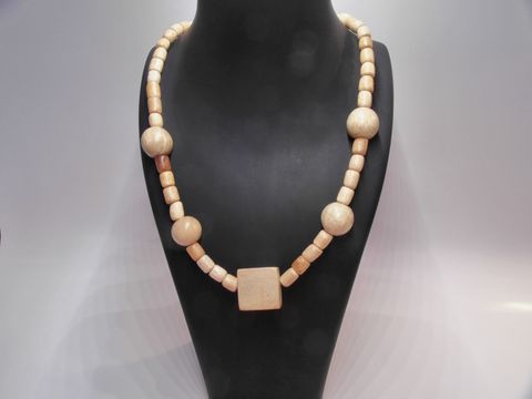 Eine naturbraune Holzkette von Juwelier Harnisch mit einer Länge von 60 cm. Die Kette besteht aus verschiedenen Holzperlen mit einem quadratischen Element in der Mitte.