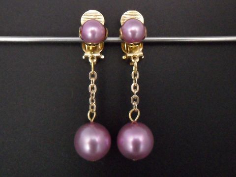 Hellrosa glänzende Ohrclips zeitlos aus Kunstharz mit goldfarbenen Elementen, hergestellt von Juwelier Harnisch, mit einem eleganten Design und asymmetrischen Perlenanhängern.