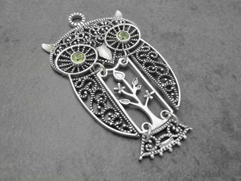 Eule aus silber mit beweglichem Körper und grünen Peridot-Steinen, im filigranen Design mit Blattmotiv, Hersteller Juwelier Harnisch, ideal als Glücksbringer.