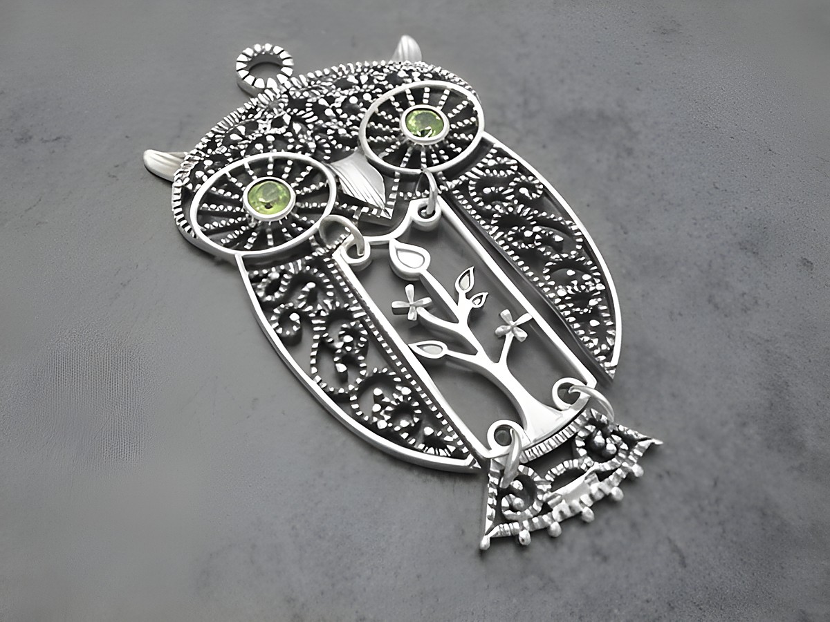 Eule aus silber mit beweglichem Körper und grünen Peridot-Steinen, im filigranen Design mit Blattmotiv, Hersteller Juwelier Harnisch, ideal als Glücksbringer.