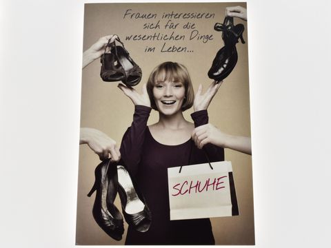 Eine Frau hält lächelnd zwei Paar Schuhe in den Händen und präsentiert eine Tüte mit der Aufschrift Schuhe. Im Hintergrund steht der Schriftzug Frauen interessieren sich für die wesentlichen Dinge im Leben.