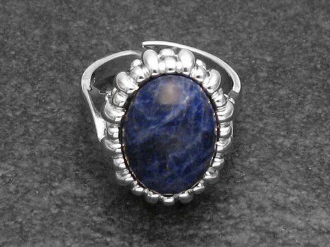Silberring mit verstellbarem Design, besetzt mit einem ovalen Sodalithstein, umgeben von einem geschwungenen, rhodinierten Rahmen, elegant und einzigartig.
