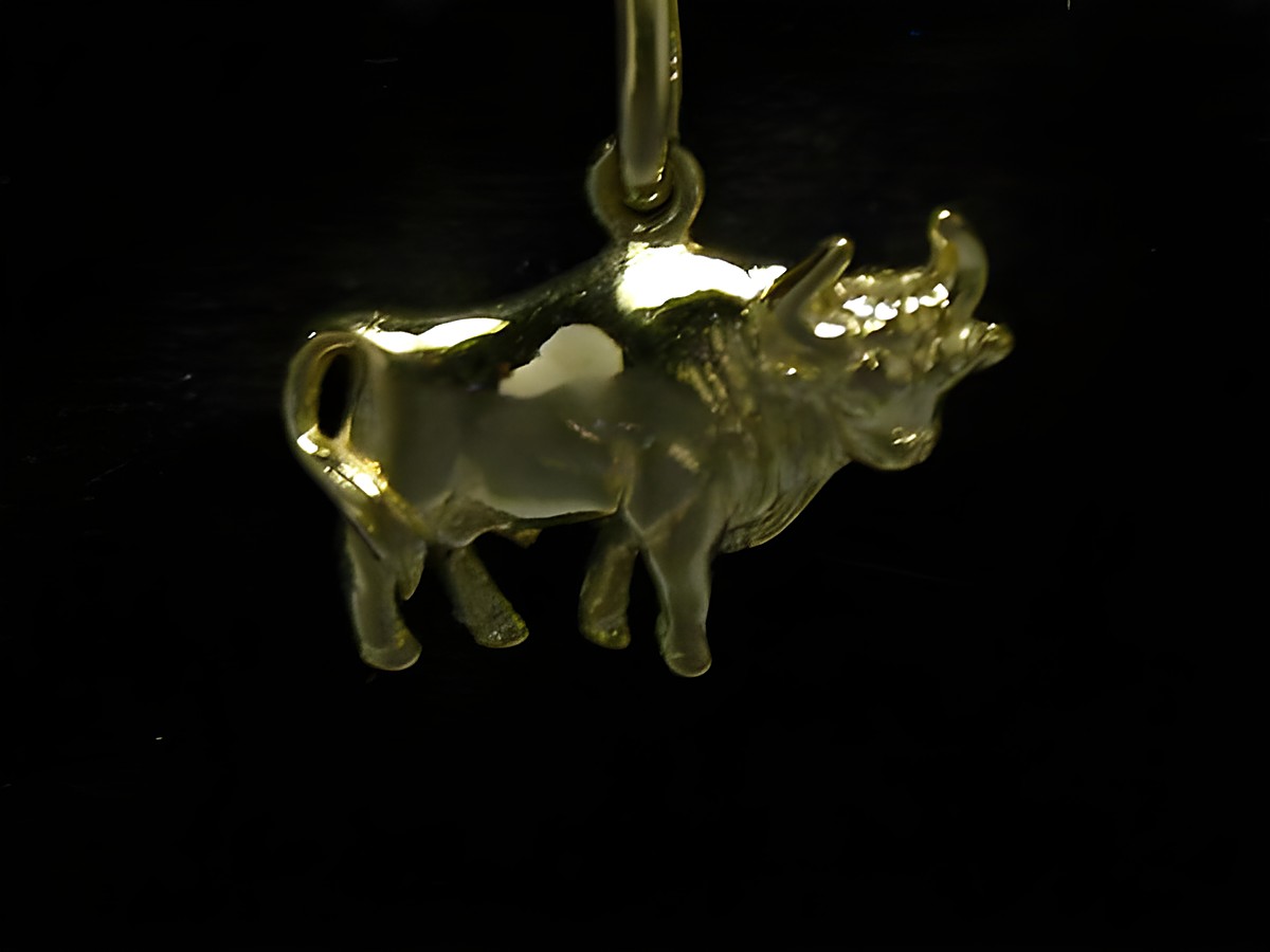 Ein plastischer Anhänger des Stiers aus poliertem Gold, hergestellt von Juwelier Harnisch, detailreich und glänzend, ideal für Sternzeichen-Liebhaber.