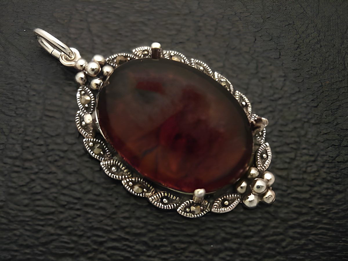 Cabochon Bernstein Silber Medaillon Anhänger in filigraner Ausführung, Hersteller Juwelier Harnisch, mit kunstvoll gestaltetem Rahmen und ovalem Bernsteinstein, idealer Schmuck für Liebhaber.