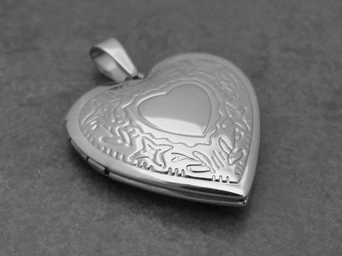 Medaillon aus Edelstahl in Herzform, nostalgisch poliert, präsentiert filigrane Muster und ein zentrales Herzmotiv, Hersteller Juwelier Harnisch, ideal für persönliche Erinnerungen.