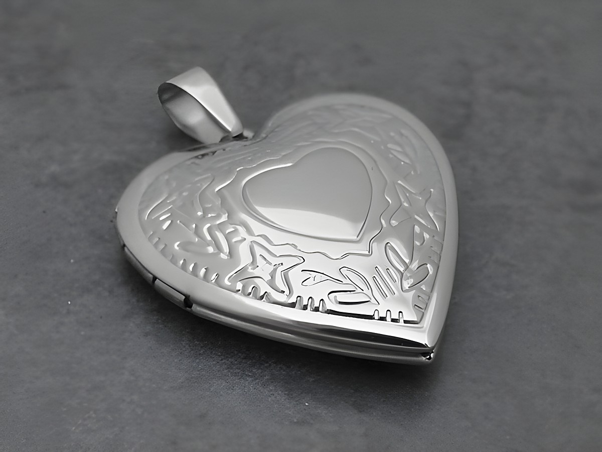Medaillon aus Edelstahl in Herzform, nostalgisch poliert, präsentiert filigrane Muster und ein zentrales Herzmotiv, Hersteller Juwelier Harnisch, ideal für persönliche Erinnerungen.