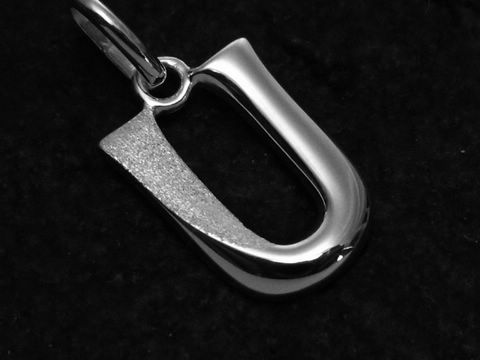 Ein teilmattierter Anhänger in Form des Buchstabens U aus Sterling Silber vom Juwelier Harnisch, glänzende und mattierte Flächen betonen das elegante Design.
