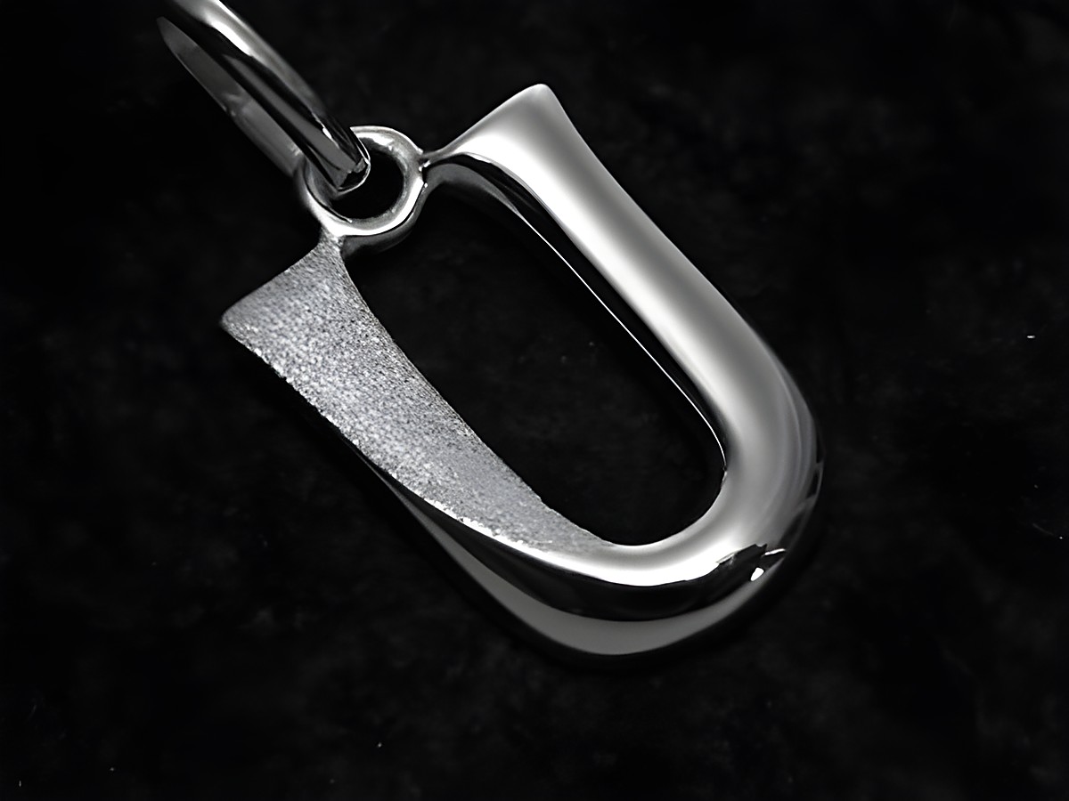 Ein teilmattierter Anhänger in Form des Buchstabens U aus Sterling Silber vom Juwelier Harnisch, glänzende und mattierte Flächen betonen das elegante Design.