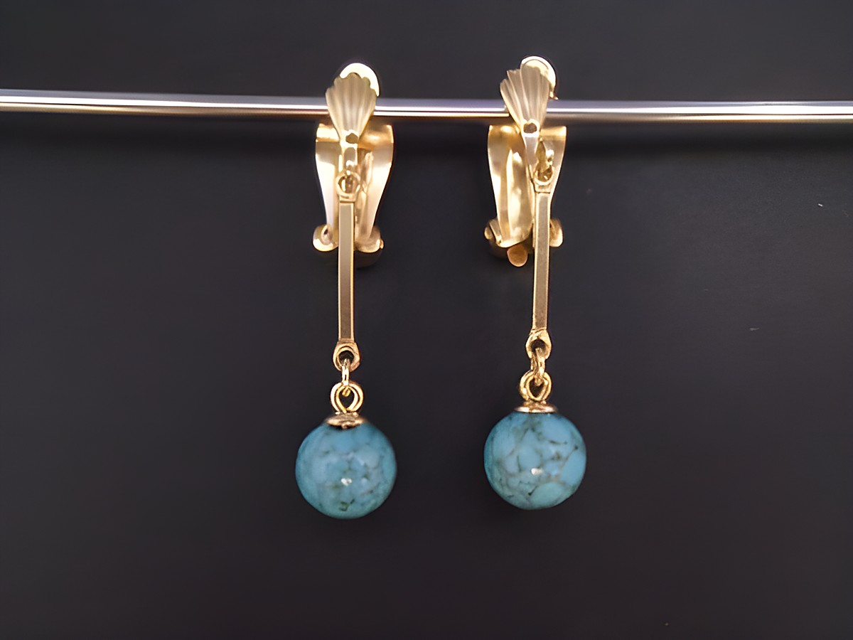Ohrclip in zeitlosem Design mit echter Goldauflage und synthetischem Türkis. Hersteller: Juwelier Harnisch. Elegantes Schmuckstück mit hängendem Türkisanhänger.
